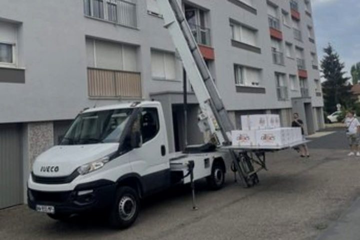 Camion monte-meubles hissant des cartons vers les étages d'un immeuble