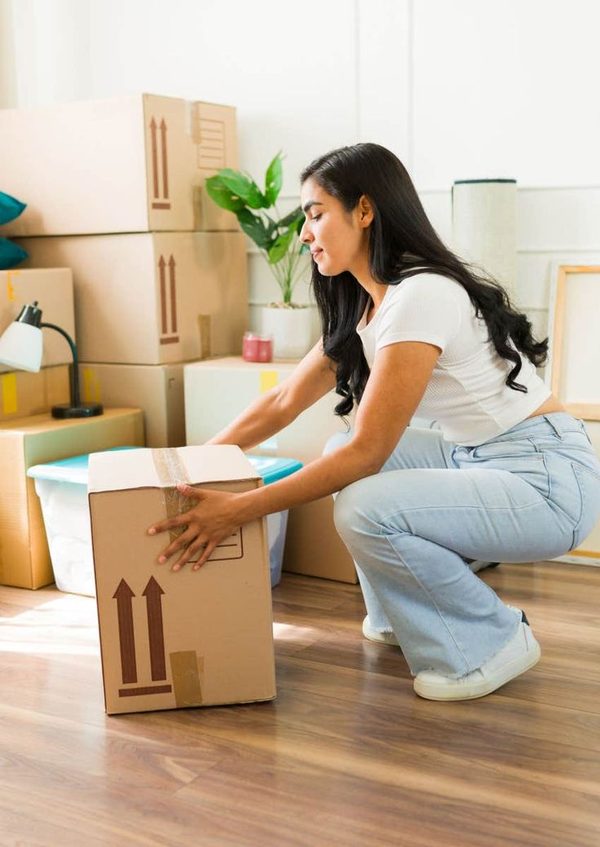 Une femme fléchit les jambes et garde le dos droit pour soulever un carton